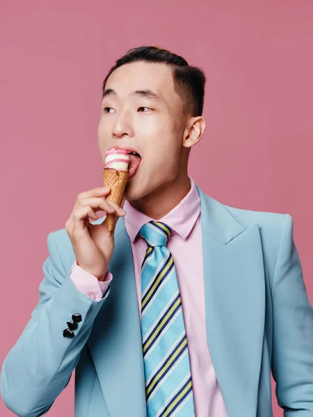 Aranyos ázsiai férfi keres fagylalt édességek rózsaszín háttér — Stock Fotó