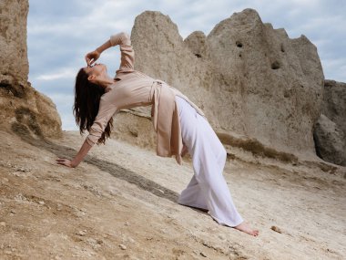 Kumda, kayaların ve yüksek taşların yanında hafif giysiler giyen bir kadın.