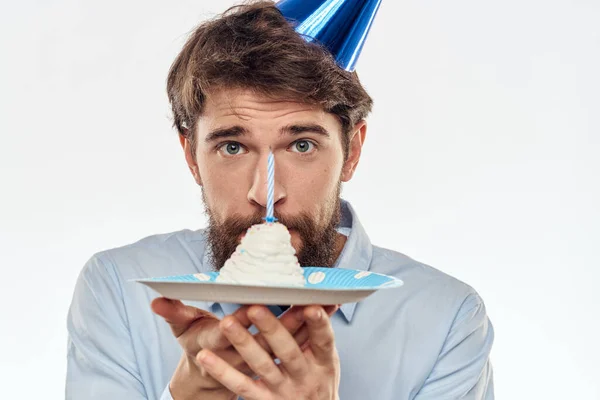 Un hombre con un plato de pastel y una camisa azul sobre un fondo claro fiesta de cumpleaños gorra corporativa — Foto de Stock