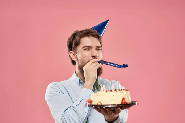 Man with cake in a plate and in a blue shirt on a pink background birthday holidays cropped view