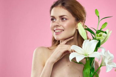 Pembe arka planda çiçekli güzel bir kadın makyaj modeli.