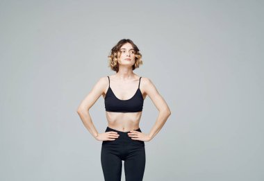 Lolipoplu yabancı bir kadın gri bir arka planda fitness yapıyor.