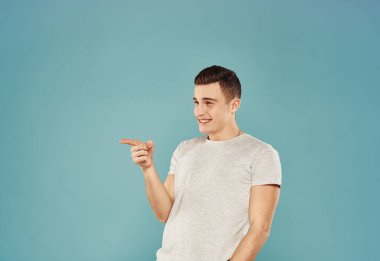 Yakışıklı adam tişört duyguları el hareketleriyle mavi arkaplan.