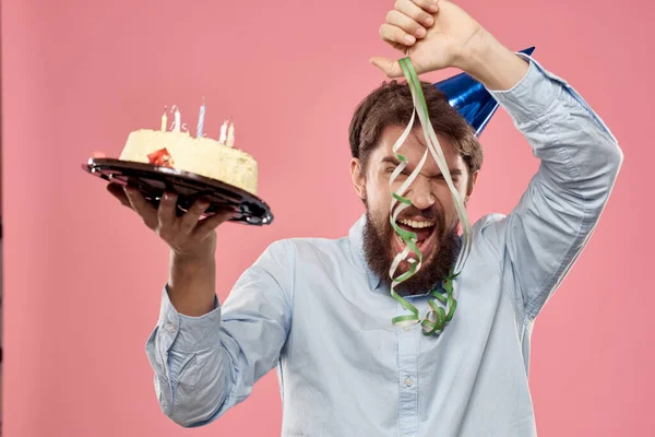 Homme barbu avec gâteau sur fond rose émotions vue recadrée — Photo