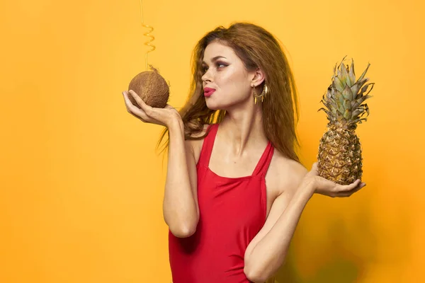 Nő ananásszal és kókusz koktél egzotikus gyümölcsök nyári életmód sárga háttér — Stock Fotó