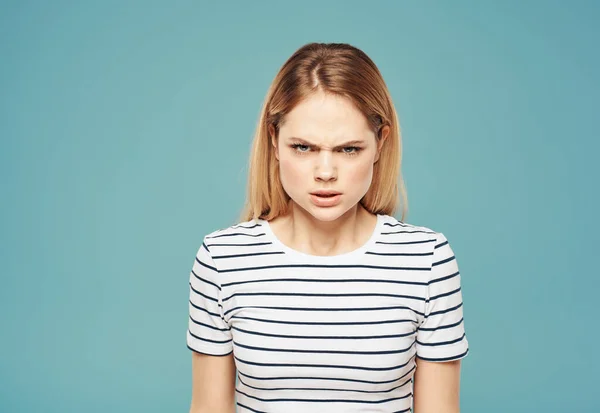 Porträt einer Frau auf blauem Hintergrund in gestreiftem T-Shirt erregt Irritation — Stockfoto