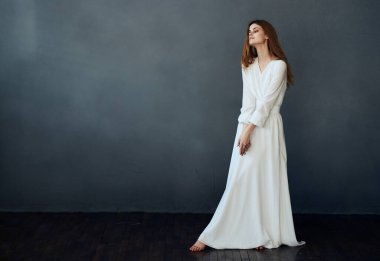 Güzel kadın beyaz elbise stüdyosu dans gri arka plan modeli yapıyor.