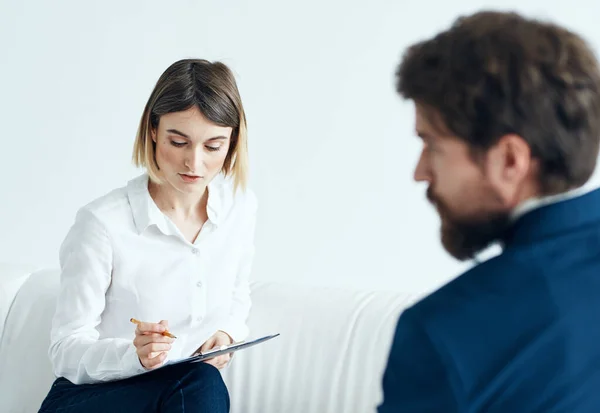 Egy nő dokumentumokkal hallgatja meg egy férfi problémáit egy könnyű hátterű pszichológussal. — Stock Fotó