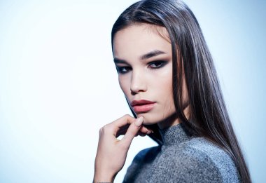 Gri kazak makyajlı güzel esmer kadının portresi.