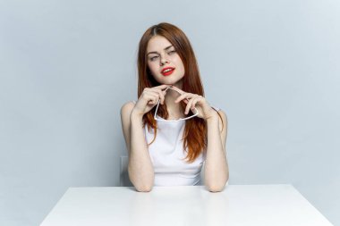 Kırmızı dudaklı zarif bir kadın masa bardaklarında oturuyor. 