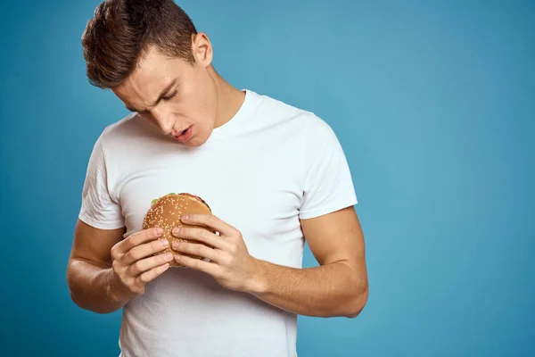 Hombre usando blanco camiseta hamburguesa dieta comida rápida fondo azul — Foto de Stock