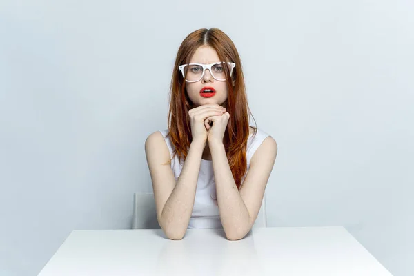 戴眼镜的优雅女人坐在餐桌旁红唇工作室的生活方式 — 图库照片