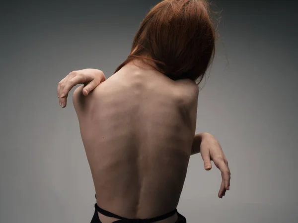 Naken kvinna vidrör sig själv med händerna på en ljus bakgrund modell beskuren vy — Stockfoto