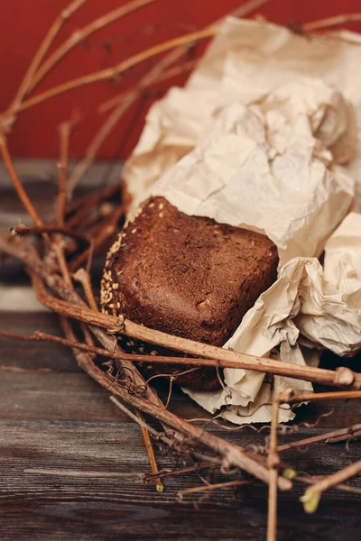 Ржаной хлеб в гнезде на деревянном столе на красном фоне — стоковое фото