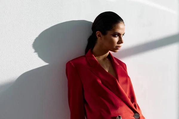 Retrato de uma mulher em uma jaqueta vermelha em um fundo leve maquiagem terno morena — Fotografia de Stock