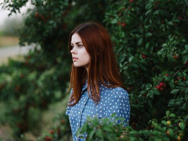 Yeşil çalıların yanında güzel bir kadın ve parkta kırmızı böğürtlenler.