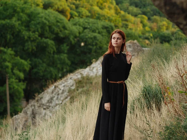 Uma mulher de vestido preto está andando nas montanhas na natureza no outono — Fotografia de Stock