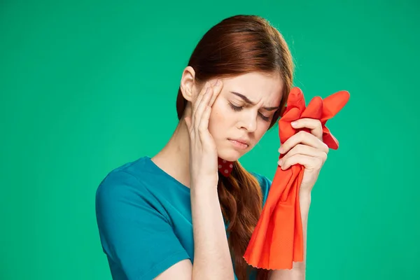 emotional woman with displeased facial expression holding rubber and red gloves cleaning