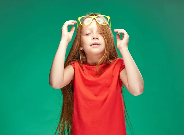 Aranyos vörös hajú lány szemüveges fején piros póló Studio Zöld háttér — Stock Fotó