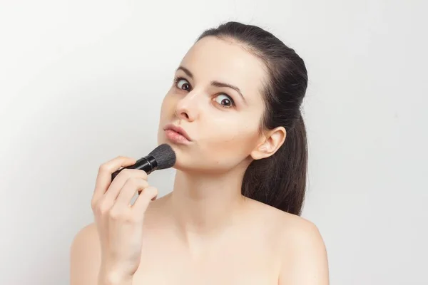 Mulher aplicando máscara com escova de maquiagem para enfrentar ombros nus — Fotografia de Stock