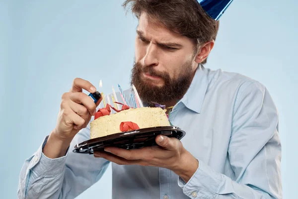 Мужчина в рубашке с тортом в руках и праздничной кепкой на голове — стоковое фото
