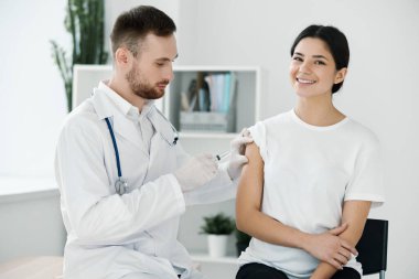 the doctor injects the vaccine into the patients shoulder hospital and protective gloves infection