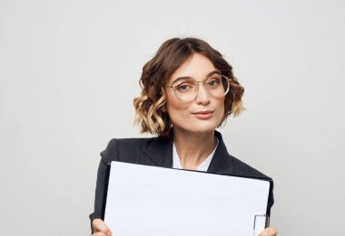 İş elbisesi giymiş beyaz kağıtlı bir kadın iş gözlükleri modelleme yapıyor.