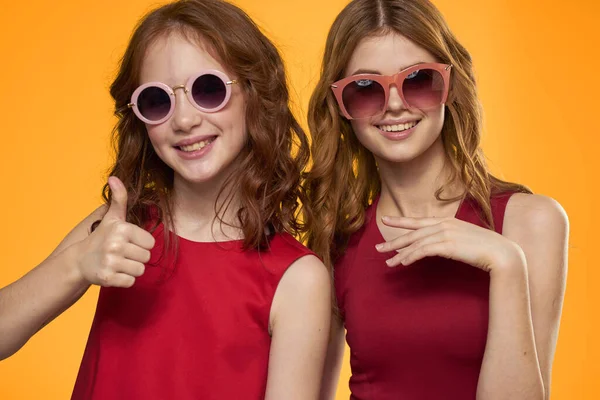 Alegre mamá e hija usando gafas de sol estilo de vida amistad familia amarillo fondo estudio — Foto de Stock