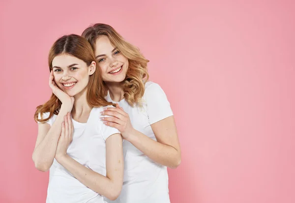 Beyaz tişörtlü iki kız arkadaş iletişim mutluluğunu kucaklıyor. — Stok fotoğraf