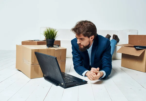 Un homme d'affaires est allongé sur le sol devant un ordinateur portable, travaille sans rien déballer — Photo