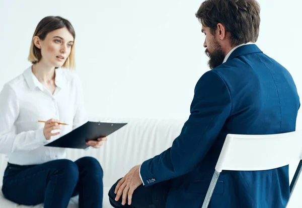 A woman with documents listens to the problems of a man on a light background psychologist — Stock Photo, Image