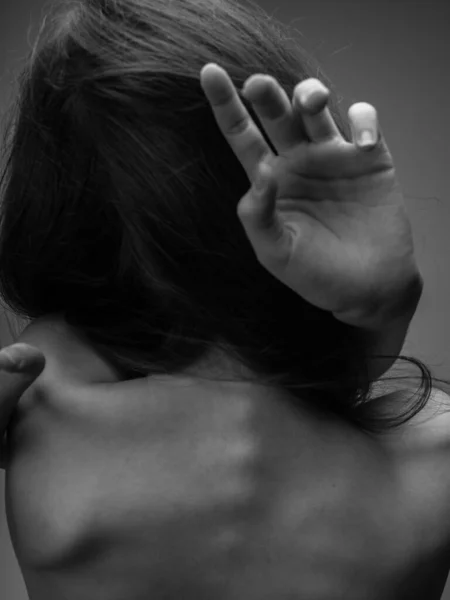 De vrouw op de grijze foto raakt zichzelf aan met haar blote rug. — Stockfoto