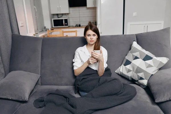Women on sofa with mobile phone and gray plaid comfort front view — Fotografia de Stock