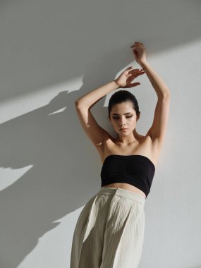 Duvara yaslanmış, el ele tutuşan bir kadın moda cazibesi.