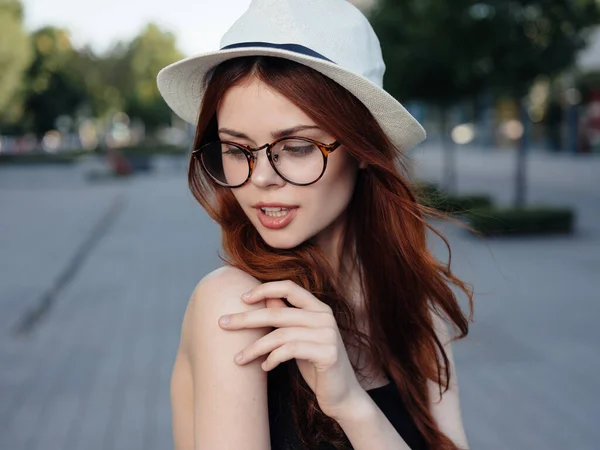 Donna attraente che cammina per strada indossando cappello e occhiali — Foto Stock