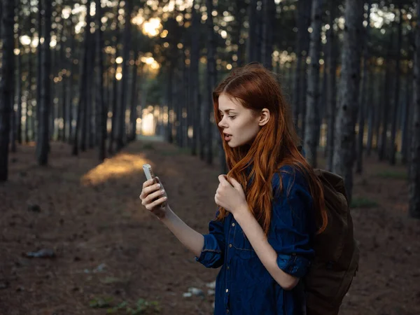 Mujer feliz en bosque de pinos con teléfono móvil navegador modelo turístico —  Fotos de Stock