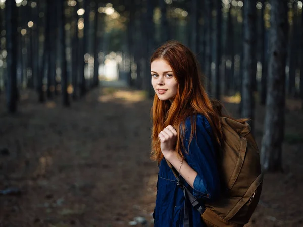 Mujer feliz excursionista en el bosque con una mochila en su espalda en otoño en la naturaleza —  Fotos de Stock