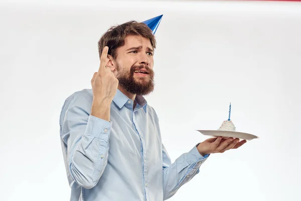 Un hombre con barba sostiene un pastel en su mano sobre un fondo claro cumpleaños — Foto de Stock