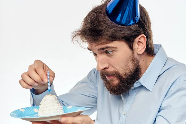 Человек с тарелкой торта и в голубой рубашке на светлом заднем плане день рождения корпоративная кепка — стоковое фото