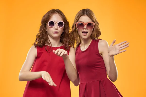 Alegre mamá e hija usando gafas de sol estilo de vida amistad familia amarillo fondo estudio — Foto de Stock