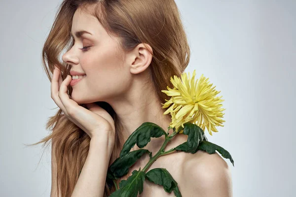 Retrato de uma mulher bonita com uma flor amarela em um fundo leve encantador sorriso modelo de cabelo vermelho — Fotografia de Stock