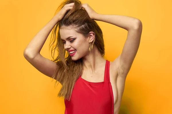 Mooie vrouw golvend haar rode tank top mode levensstijl cosmetica gele achtergrond — Stockfoto