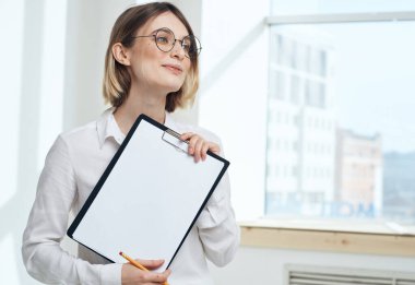 Pencerenin yanında doküman klasörlü kadın görüntüsü