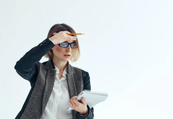 Женщина с блокнотом и ручкой в руках на легком фоне делового финансового костюма — стоковое фото