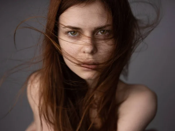 Regard offensé d'une femme aux cheveux roux sur un fond gris épaules nues gros plan — Photo
