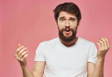 Pembe arka planda beyaz tişörtlü bir adamın portresi eğlenceli duyguların görüntüsüydü.