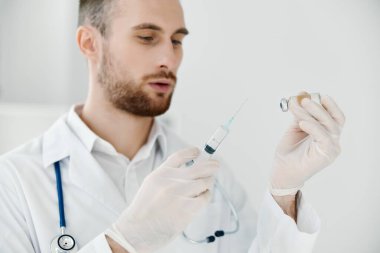 Doktor elinde aşı ampulü ve şırınga iğnesi olan tıbbi eldivenler stetoskop covid. 