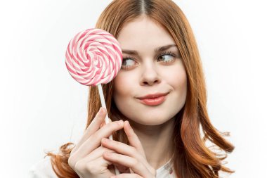 Yüzünün yanında yuvarlak lolipopu olan neşeli, güzel bir kadın.