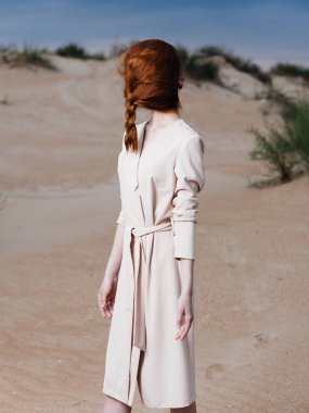 Uzun boylu, kızıl saçlı, yüzünde atkuyruğu olan, kırmızı ayakkabılı bir kadın.