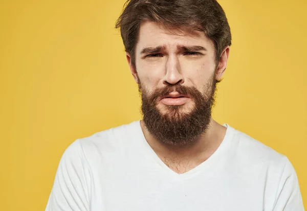 Homem emocional em um fundo amarelo em uma t-shirt branca modelo morena de barba grossa — Fotografia de Stock